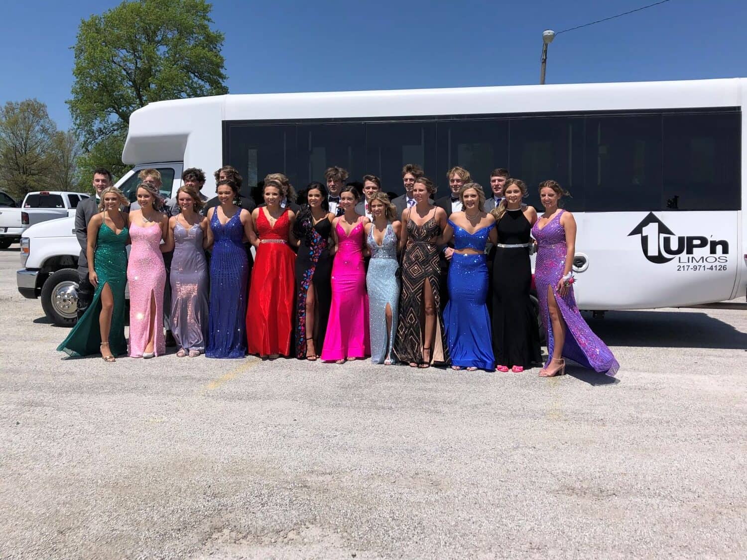 1Up'n Limousines Group Photo Group of women in colorful dresses standing in front of a limousine.