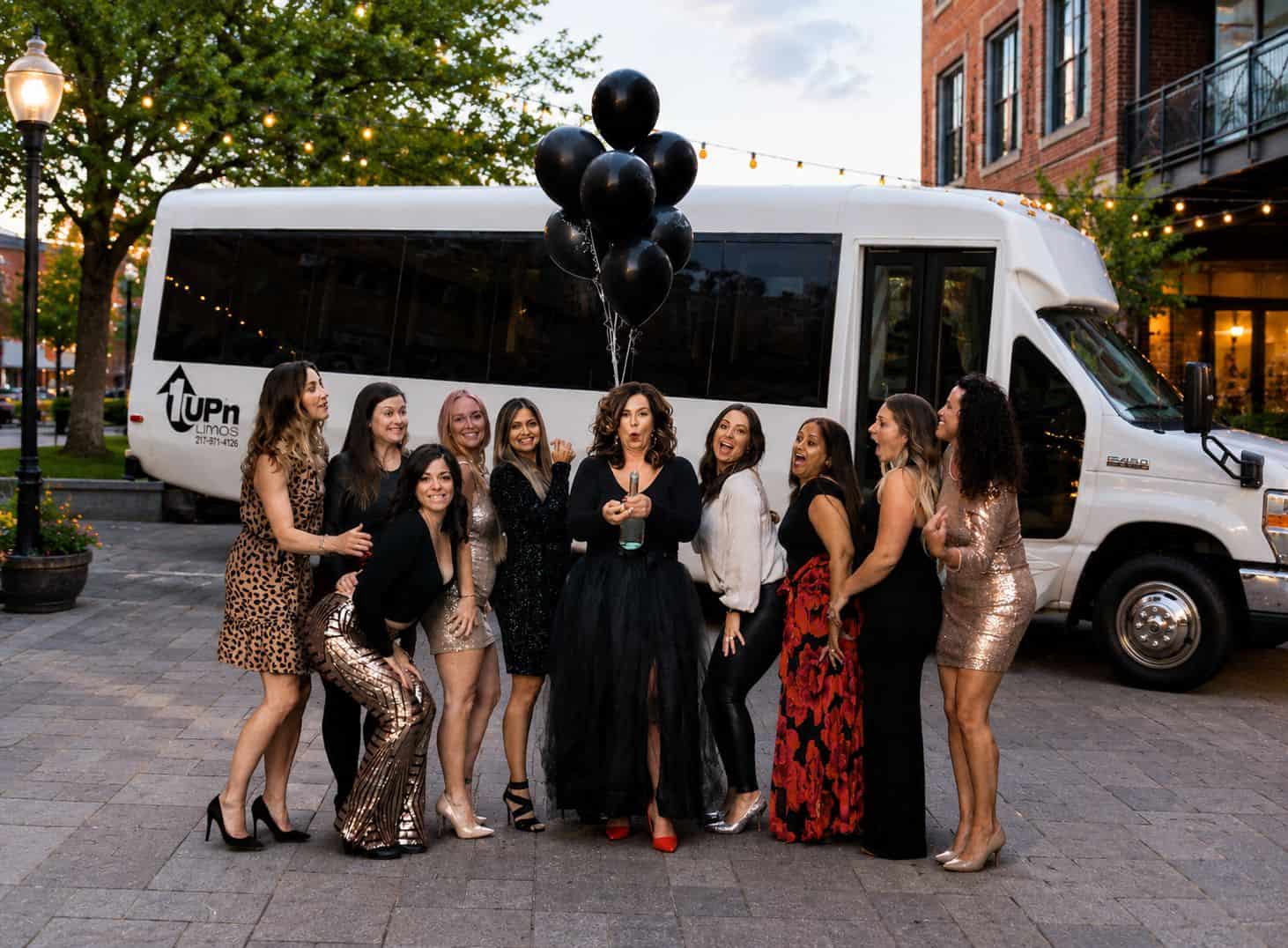 1Up'n Limousines Group Event Group of women celebrating with limousine and balloons in city.