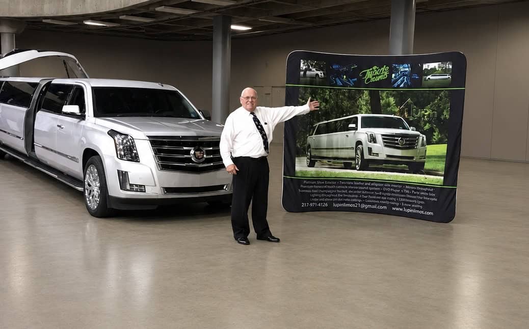 Man standing next to a Cadillac limousine at 1Up'n Limousines.